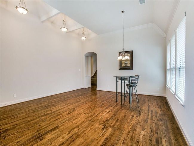 Unfurnished dining area featuring arched walkways, plenty of natural light, dark wood finished floors, and high vaulted ceiling | Image 4