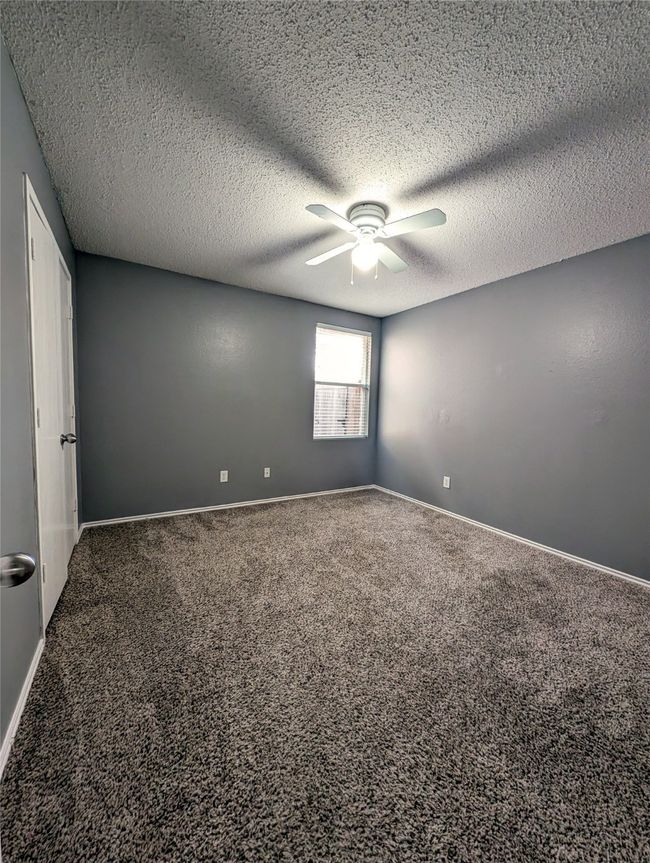 Empty room with a ceiling fan, carpet floors, a textured ceiling, and baseboards | Image 13