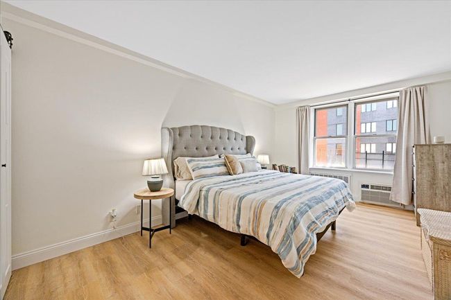 Bedroom featuring light wood-style floors, baseboards, a wall mounted AC, and crown molding | Image 10