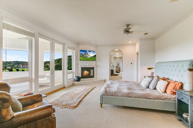 Bedroom featuring carpet floors, arched walkways, ornamental molding, access to outside, and a glass covered fireplace | Image 21