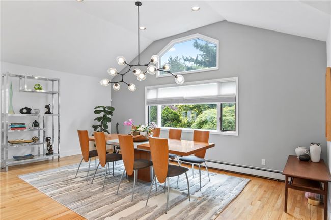 Dining space featuring baseboard heating, wood finished floors, a chandelier, and high vaulted ceiling | Image 14