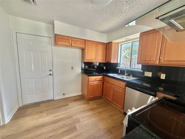 Kitchen with electric range, stainless steel dishwasher, light wood finished floors, a textured ceiling, and decorative backsplash | Image 5