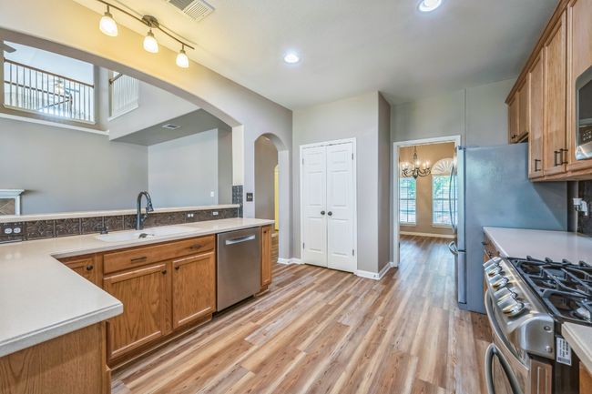 Kitchen featuring stainless steel appliances, arched walkways, a sink, brown cabinets, and light countertops | Image 12