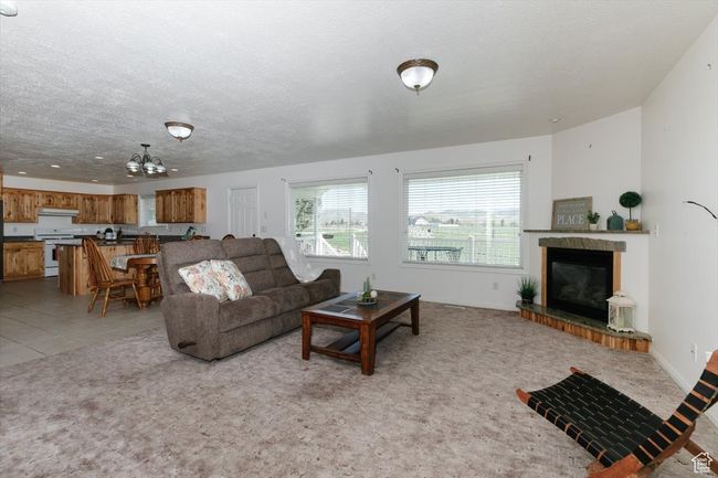 Living room featuring a tiled fireplace, a chandelier, a textured ceiling, and light carpet | Image 21