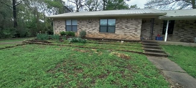 View of front of house featuring brick siding, covered porch, a metal roof, and a front lawn | Image 6