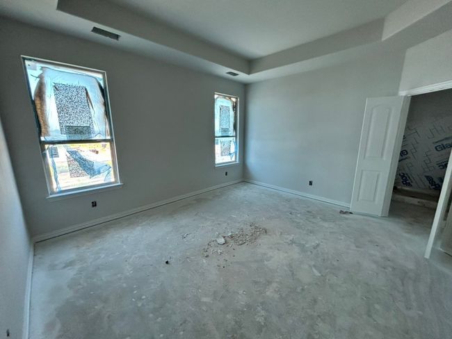 Unfurnished bedroom with a tray ceiling and concrete flooring | Image 8