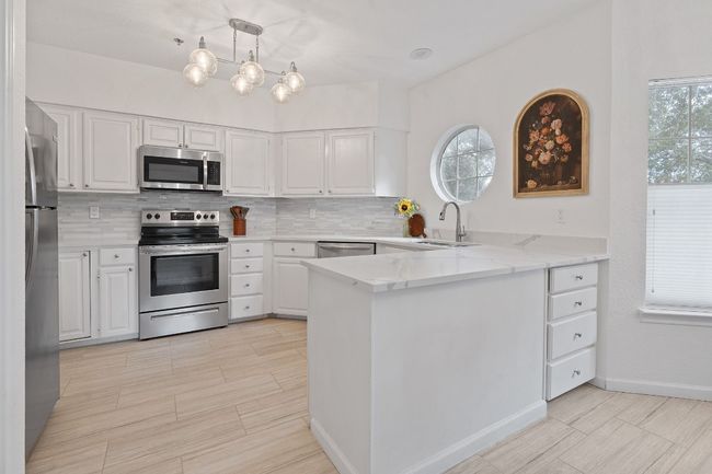 Kitchen and breakfast bar with new quartz countertops and beautiful floors. | Image 8