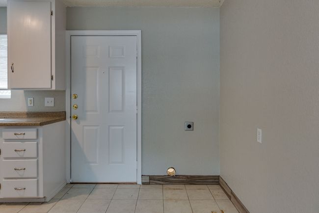 Laundry room with light tile patterned floors, hookup for an electric dryer, laundry area, and baseboards | Image 8