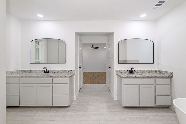 Bathroom with two vanities, a freestanding tub, wood finished floors, a ceiling fan, and recessed lighting | Image 25
