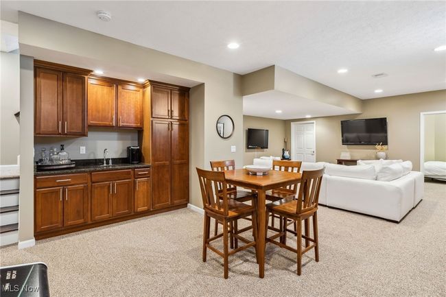 Open, inviting basement with a built-in bar and relaxed dining area | Image 31
