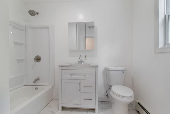 Full bath with a baseboard radiator, marble finish floors, vanity, toilet, and shower / bath combination | Image 28