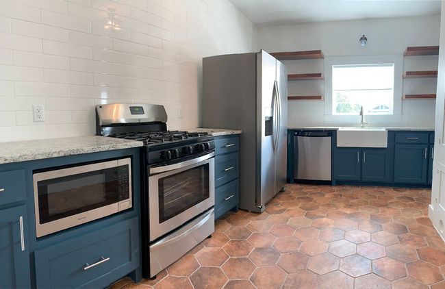 Kitchen with stainless steel appliances, open shelves, blue cabinetry, and tasteful backsplash | Image 8