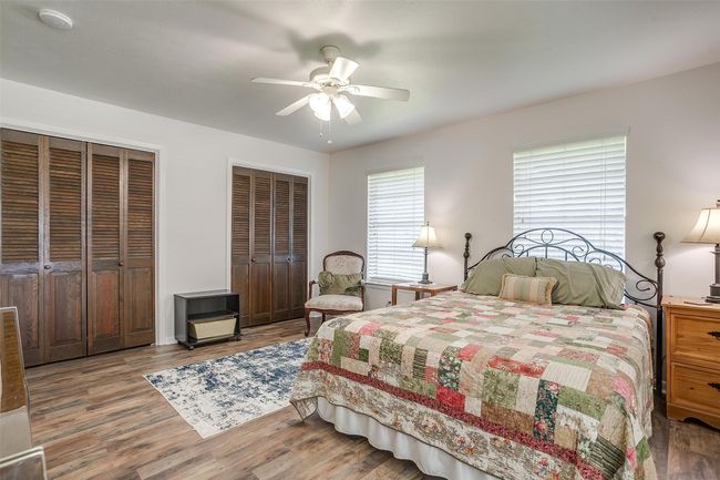 Bedroom with multiple closets, wood finished floors, and a ceiling fan | Image 23