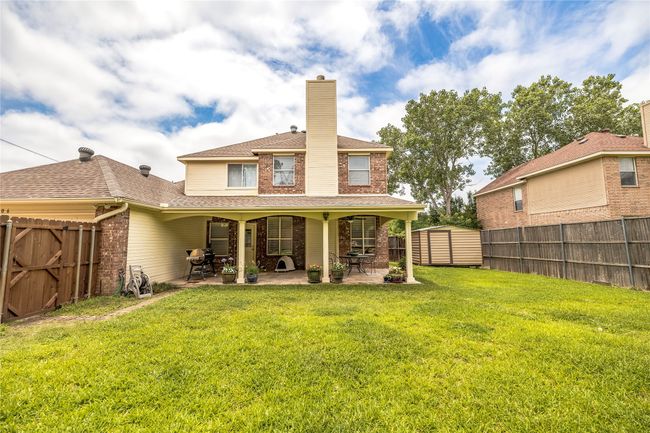 Back of house featuring a patio area, a chimney, a shingled roof, and brick siding | Image 37