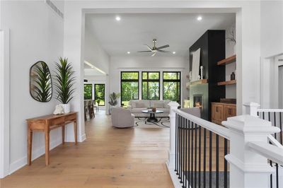 Living room with a large fireplace, built in features, ceiling fan, and light hardwood / wood-style flooring | Image 3