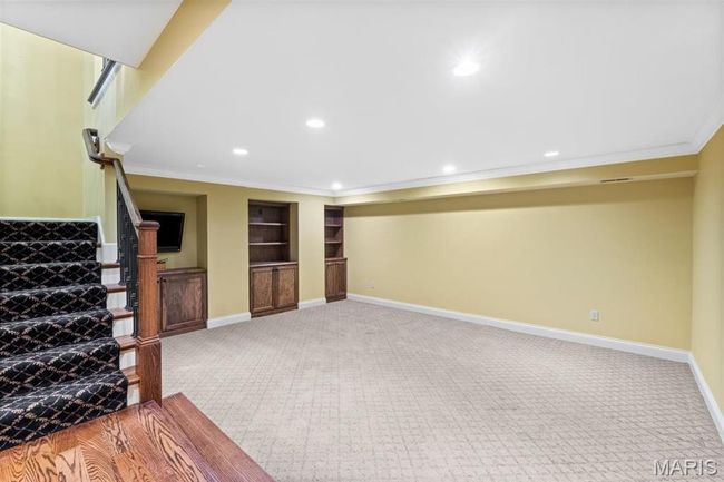 Finished below grade area featuring carpet, stairway, crown molding, recessed lighting, and built in features | Image 44
