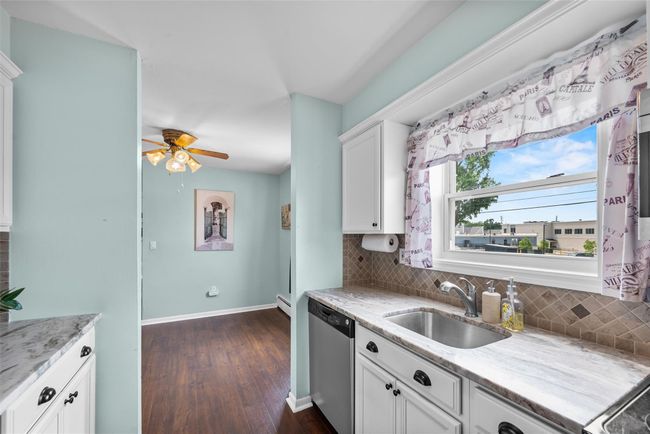 Kitchen featuring dishwasher, decorative backsplash, dark wood-type flooring, white cabinets, and ceiling fan | Image 17