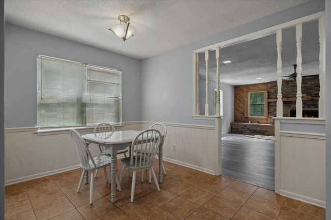 Dining area with a textured ceiling, wainscoting, wood walls, and tile patterned floors | Image 17