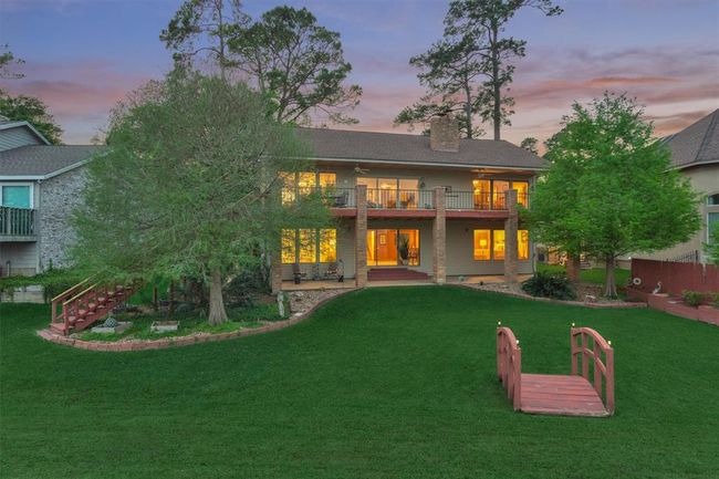 The home is beautifully illuminated at night, creating a warm and inviting presence. This view captures the property as seen from the lake side. | Image 36