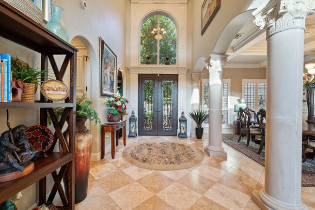 Entrance foyer with decorative columns, a high ceiling, arched walkways, crown molding, and french doors | Image 12