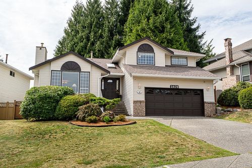 Beige siding exterior with a brown garage door, brick accents, and a paved driveway | Card Image