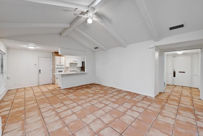 Unfurnished living room featuring ceiling fan, baseboards, vaulted ceiling with beams, and visible vents | Image 5