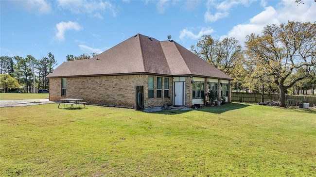 Rear view of property with brick siding, roof with shingles, fence, and a yard | Image 4