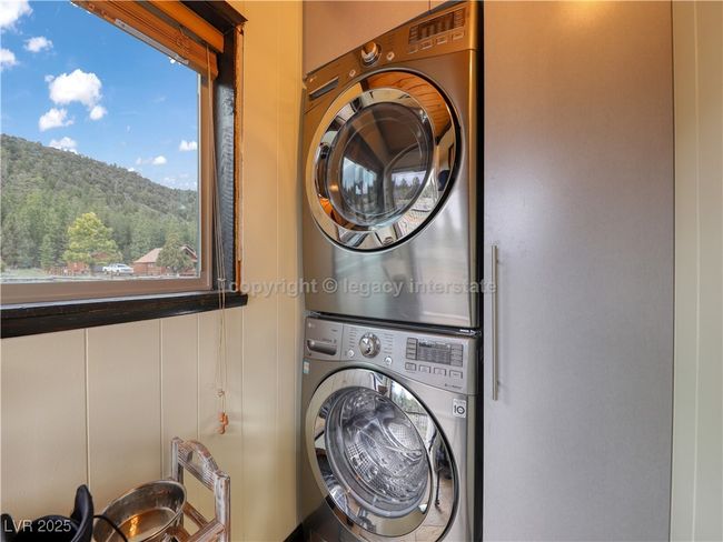 Washroom featuring stacked washer / drying machine and a wealth of natural light | Image 29