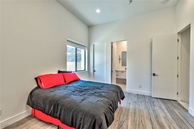 Bedroom with baseboards, wood finished floors, and ensuite bathroom | Image 11
