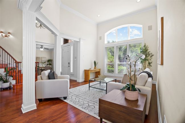 Living area with ornate columns, healthy amount of natural light, a high ceiling, dark wood-type flooring, and a ceiling fan | Image 22