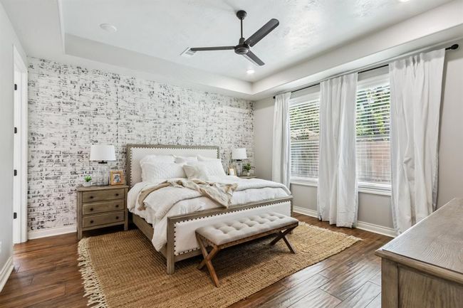 The spacious primary bedroom is a true retreat, featuring a striking German schmear accent wall and windows that offer tranquil views overlooking the backyard. | Image 18