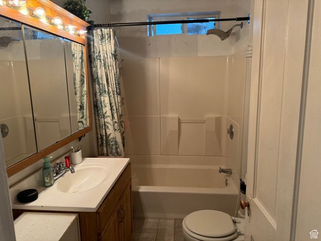 Full bath with tile patterned floors, shower / bath combo with shower curtain, vanity, and toilet | Image 18