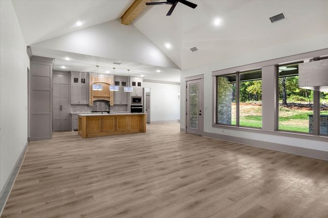 Kitchen featuring open floor plan, glass insert cabinets, beamed ceiling, light countertops, and light wood finished floors | Image 6
