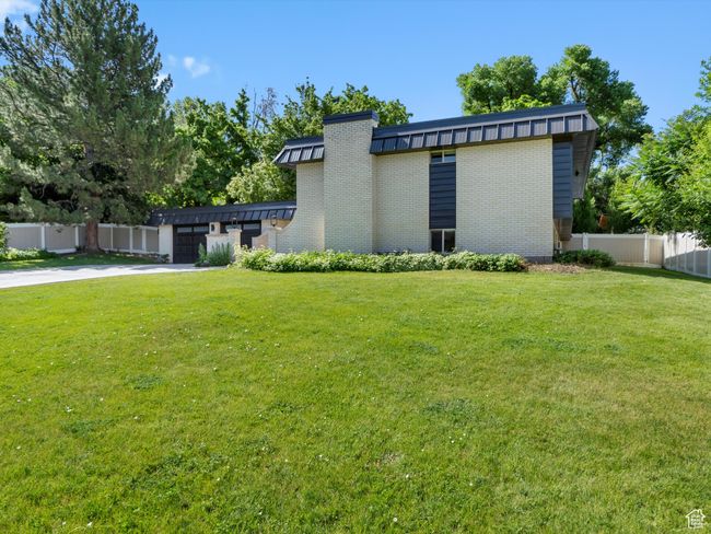 View of side of home with brick siding, a garage, concrete driveway, and a standing seam roof | Image 44