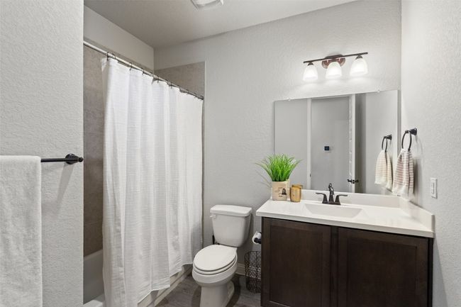 Full bathroom with vanity, a textured wall, shower / bath combo with shower curtain, and wood finished floors | Image 25