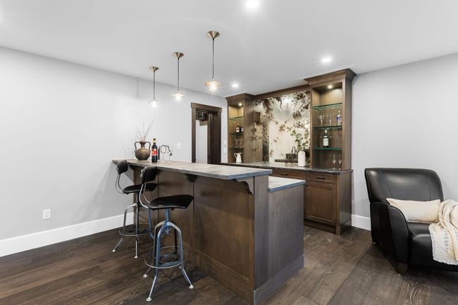Indoor wet bar with dark wood-type flooring, baseboards, hanging light fixtures, and recessed lighting | Image 28