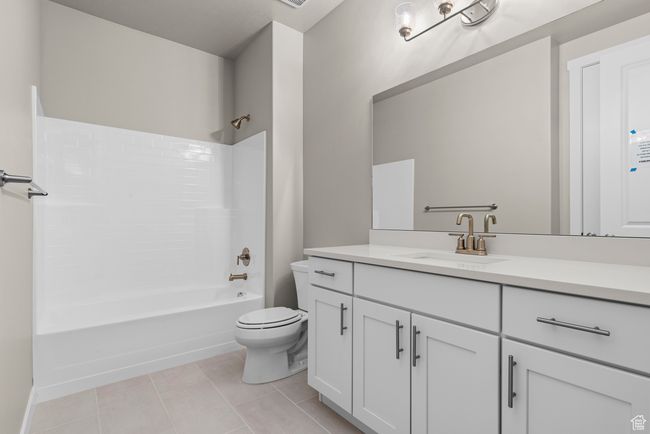Bathroom with toilet, vanity, tub / shower combination, and tile patterned flooring | Image 4