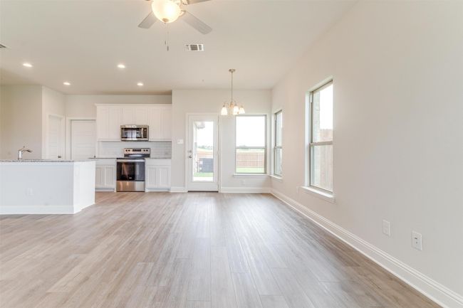 Unfurnished living room featuring ceiling fan with notable chandelier and light hardwood / wood-style floors | Image 11