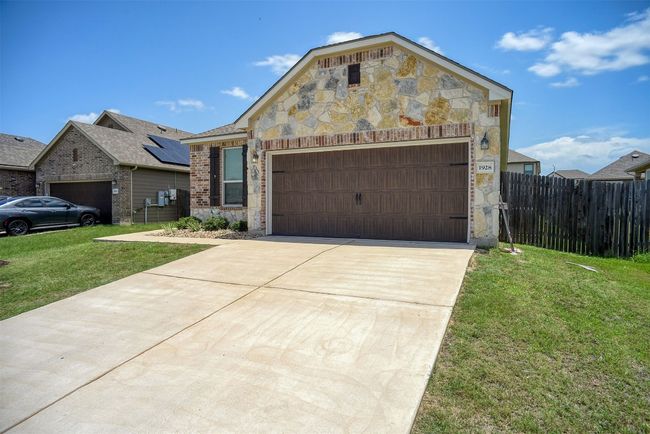 View of front facade featuring stone siding, a garage, brick siding, and driveway | Image 12