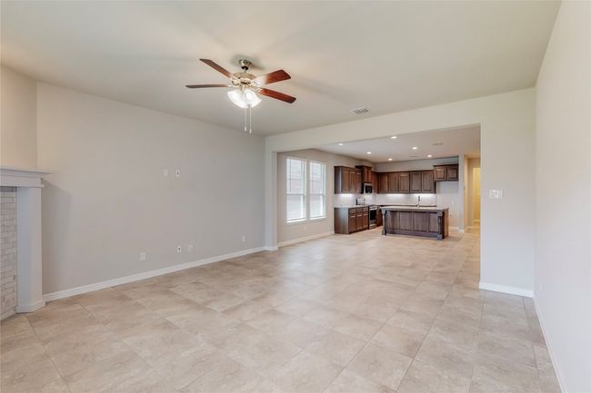 Unfurnished living room featuring ceiling fan, baseboards, light tile patterned floors, recessed lighting, and a fireplace | Image 13