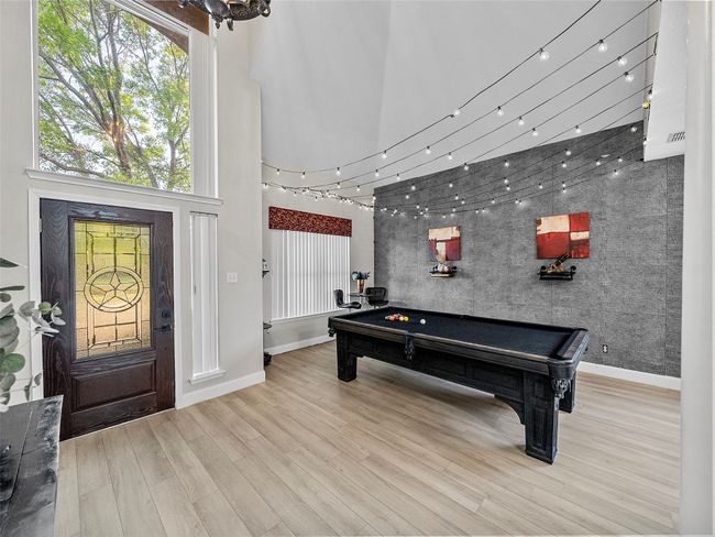 Recreation room with a towering ceiling, baseboards, an accent wall, wood finished floors, and billiards | Image 9
