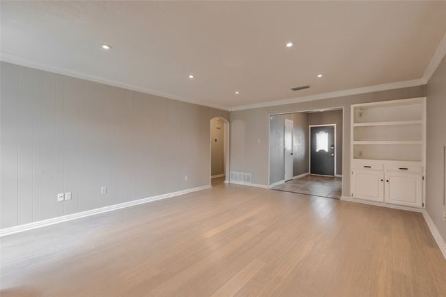 Empty room featuring arched walkways, light wood-type flooring, ornamental molding, built in features, and recessed lighting | Image 6