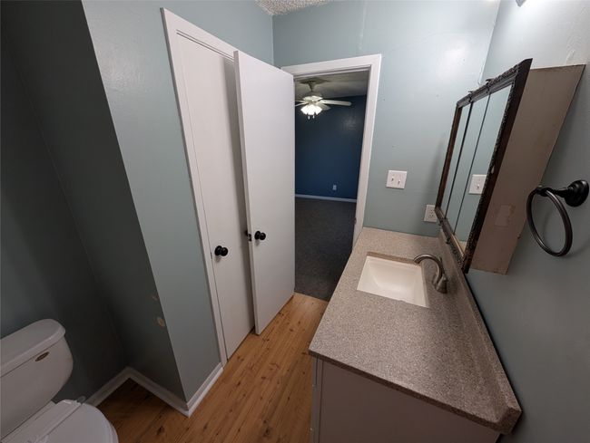 Half bathroom featuring toilet, baseboards, a ceiling fan, wood finished floors, and vanity | Image 21