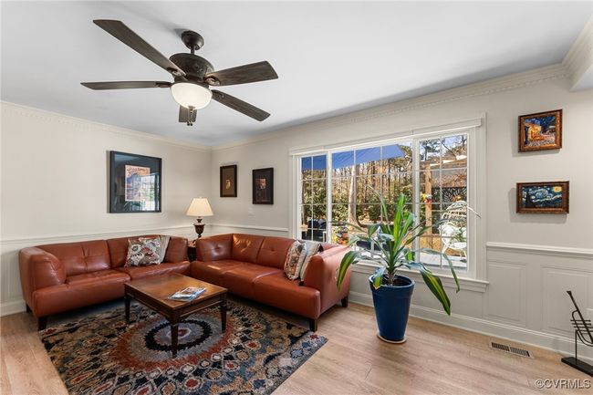 Living area featuring visible vents, ornamental molding, a ceiling fan, wainscoting, and light wood finished floors | Image 4