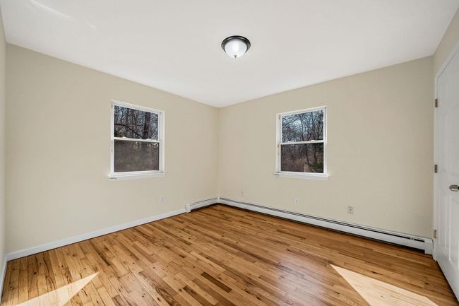 Unfurnished room with a baseboard radiator, baseboards, and wood-type flooring | Image 15