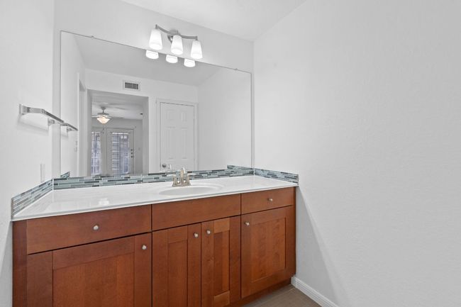 Bathroom with visible vents, backsplash, baseboards, ceiling fan, and vanity | Image 22