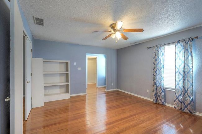 Unfurnished bedroom featuring a textured ceiling, visible vents, baseboards, ceiling fan, and wood finished floors | Image 32