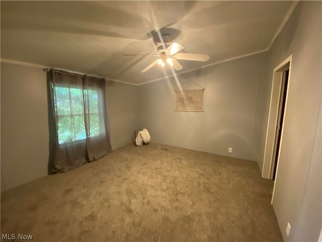 Carpeted spare room featuring ceiling fan and ornamental molding | Image 10