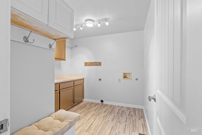 Laundry area featuring hookup for an electric dryer, cabinet space, washer hookup, and light wood-style floors | Image 23