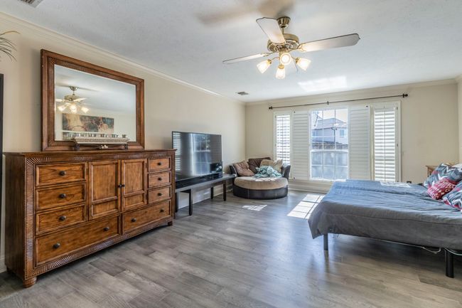Bedroom with wood finished floors, crown molding, and a ceiling fan | Image 13